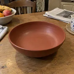 shallow matte rust-red ceramic serving bowl, as photographed