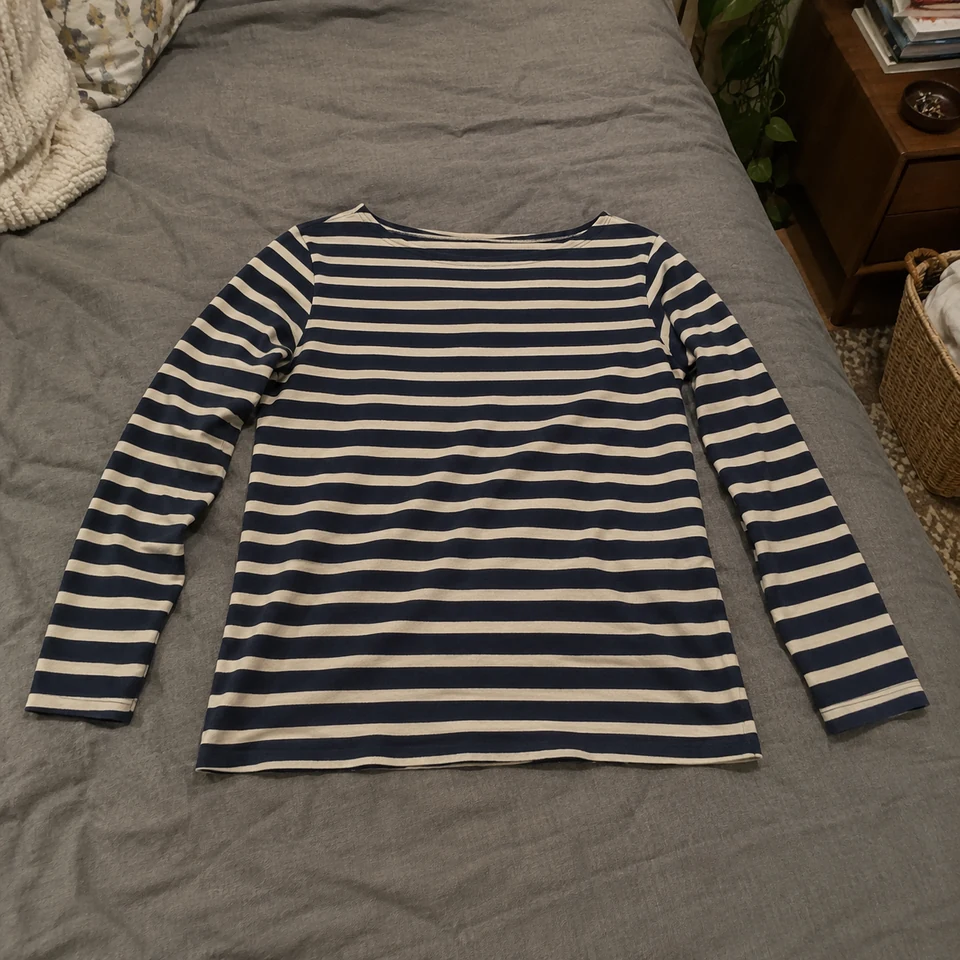 navy and cream striped long-sleeve boatneck shirt, laid flat on a bed
